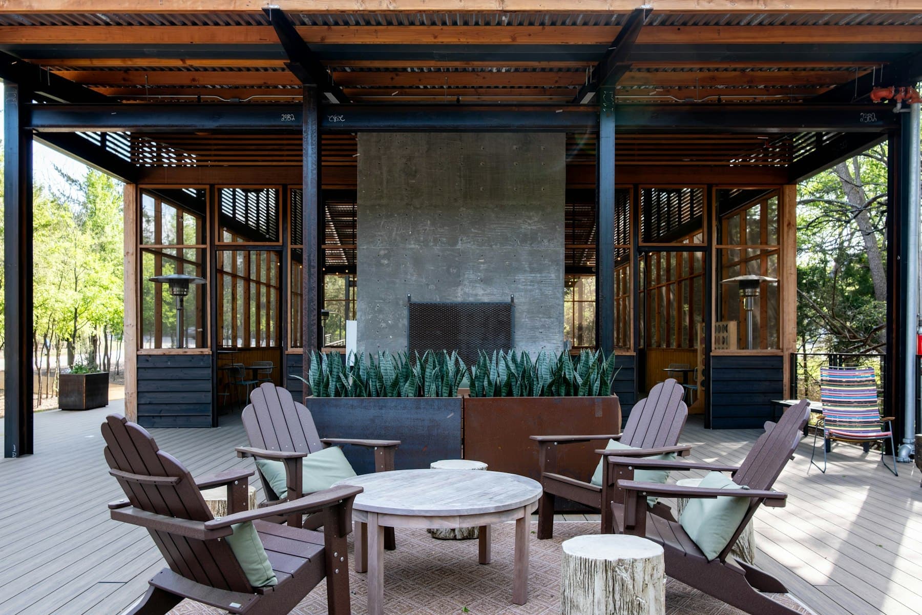 Covered terrace with an outdoor fireplace and Adirondack chairs