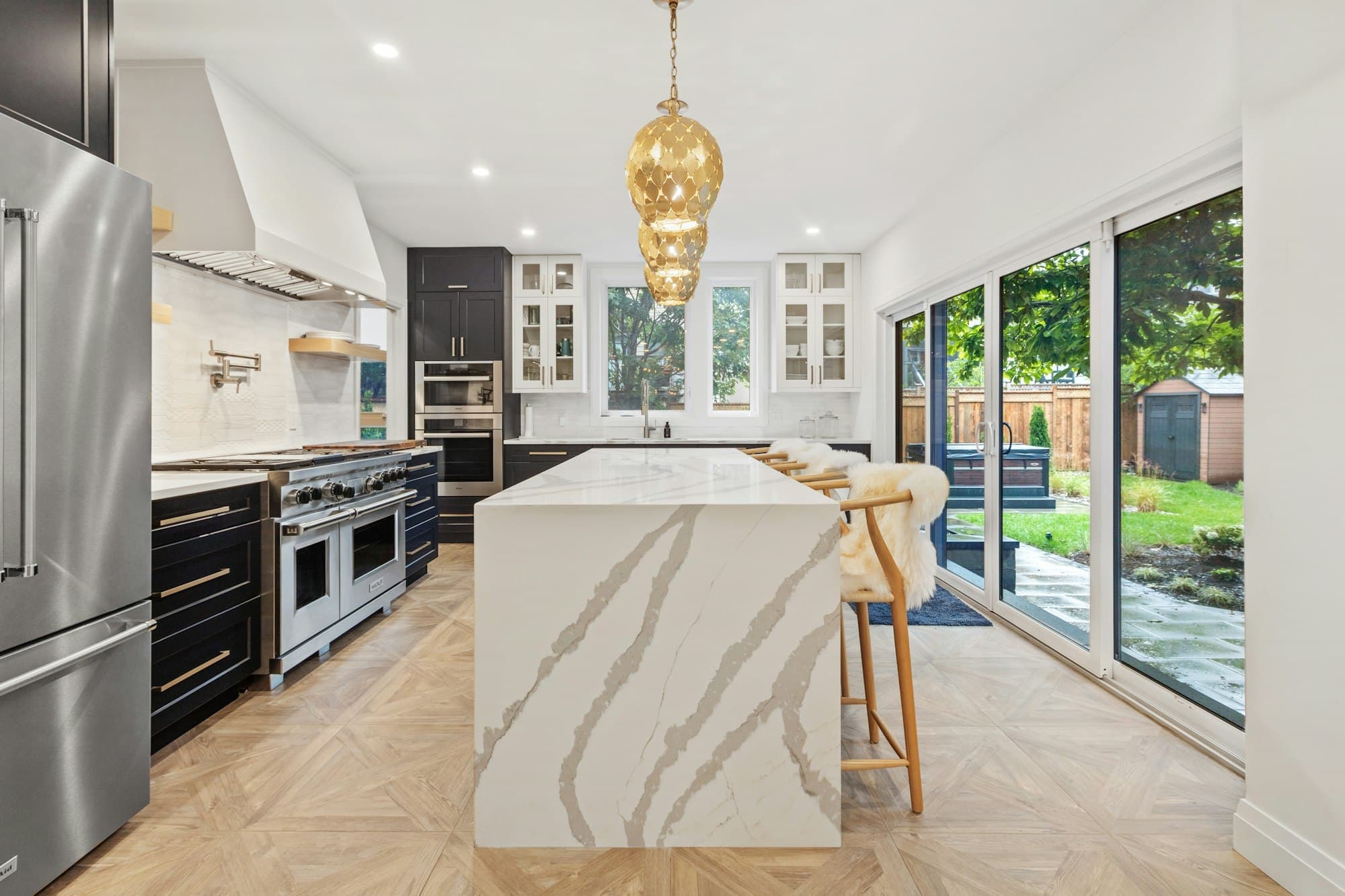 Open kitchen with a long marble island and a brass pendant