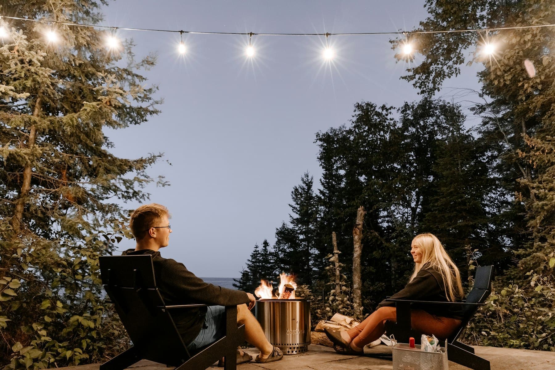 A firepit and string lights on the terrace at golden hour